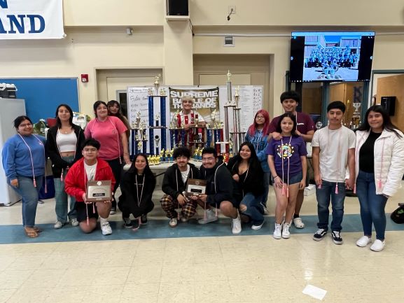 Band seniors posing in front of all their trophies